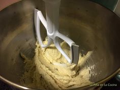 a mixing bowl filled with yellow batter and two white mixer attachments on top of it