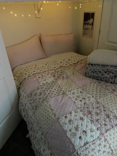 a bed that has some blankets on top of it in a room with string lights