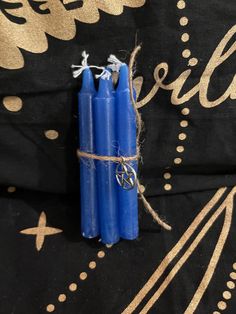 three blue candles tied with twine on black fabric