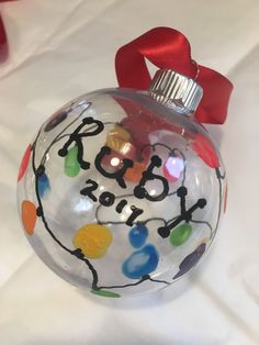 a glass ornament with the word joy written on it and a red ribbon