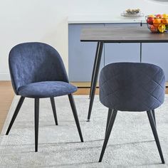 two blue chairs sitting on top of a rug next to a table with fruit in it