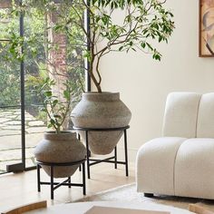 two large vases sitting next to each other in front of a white couch and window