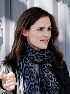 a woman wearing a black leather jacket and leopard print scarf