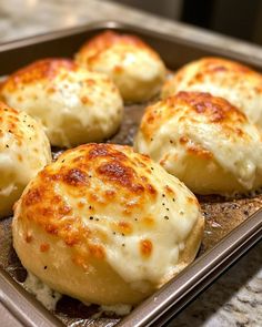 four biscuits covered in cheese sit on a baking sheet