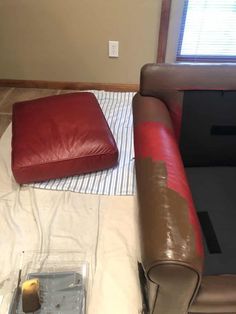 a red leather couch sitting on top of a white sheeted floor next to a window