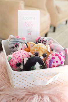 a basket filled with lots of small stuffed animals sitting on top of a pink rug