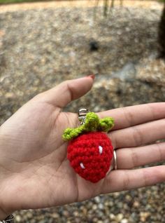 a hand holding a tiny crocheted strawberry keychain in it's palm