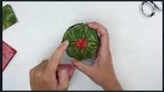 someone is making a christmas ornament out of green paper and red fabric with scissors on the table