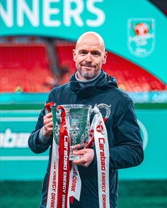 a man holding a trophy in front of a green and red stadium sign with the words liverpool on it