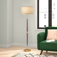 a living room with a green chair and a lamp on the floor in front of a window