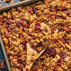 granola in a baking pan with a wooden spoon