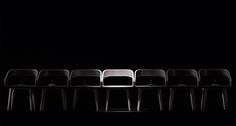 six chairs lined up in a row on a black background with one chair facing the camera