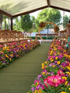 rows of wooden chairs with flowers lining the aisle to an outdoor ceremony venue in summer