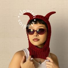 a woman wearing a knit devil hat and sunglasses