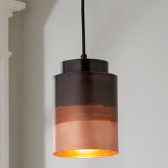 a light hanging from a ceiling in a room with a white wall and window behind it