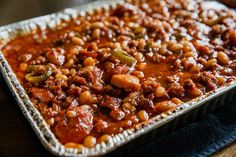 a pan filled with chili and beans on top of a wooden table