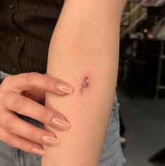 a woman's arm with a tiny red flower on the tip of her left arm