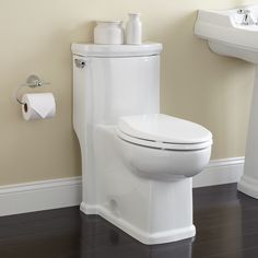 a white toilet sitting in a bathroom next to a wall mounted faucet with soap dispensers on it