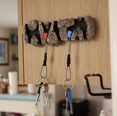 several keys hanging from hooks on a kitchen cabinet door with magnets attached to them