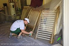 a man in white shirt and green pants working on a metal rack with an aluminum sheet covering it