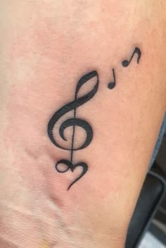 a small tattoo with musical notes on the side of the leg, and a treble