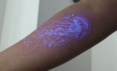 a person's arm with white ink on it and an image of a jellyfish