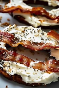 bacon and cheese bagels on a plate with sprinkled black sesame seeds around them