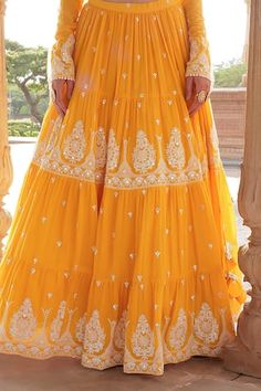 Orange lehenga with multi layered tiered panels, all over vintage pattern, tonal thread and mirror embroidery. Paired with embroidered padded blouse with churidar sleeves and dupatta with crochet cut work lace border. - Aza Fashions Embroidered Tiered Skirt Wedding Dresses, Designer Traditional Tiered Lehenga, Traditional Tiered Lehenga With Zari Work, Traditional Lehenga With Zari Work And Tiered Skirt, Designer Lehenga With Zari Work And Tiered Skirt, Designer Tiered Skirt Lehenga With Zari Work, Traditional Choli With Zari Work And Tiered Skirt, Tiered Skirt Lehenga With Zari Work, Traditional Sharara With Tiered Skirt For Reception