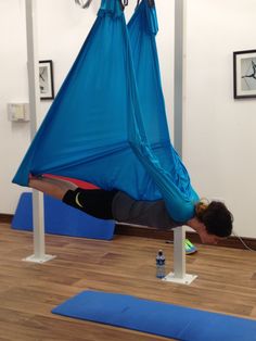 a woman is laying in a hammock on the floor and doing yoga exercises