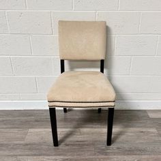 a beige upholstered chair against a white brick wall