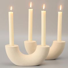 three white candles sitting on top of each other with one candle in the middle and another lit