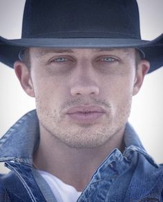 a man wearing a black cowboy hat looking at the camera with a serious look on his face