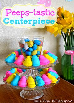 there is a vase full of yellow flowers next to a cake stand with peeps - tastic candies on it