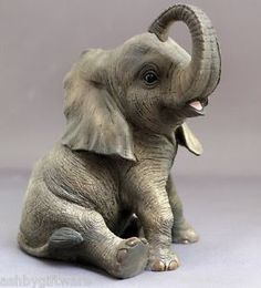 an elephant figurine sitting on the ground with its trunk up