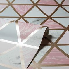 a pink and white wallpaper with gold foil on it's edges, next to a roll of tape