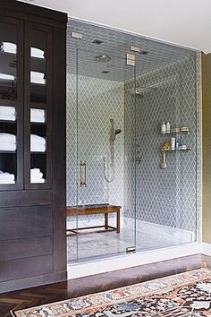 a walk in shower sitting next to a wooden bench on top of a tiled floor