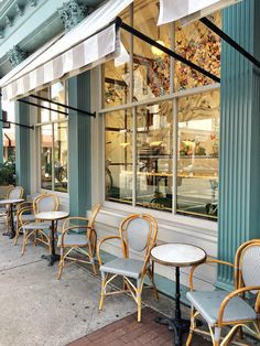 there are many chairs and tables in front of the storefront window that is empty