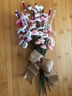 a bunch of pink and white flowers on top of a wooden table next to a bow