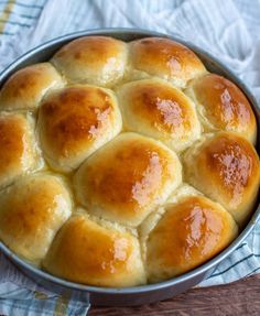 a pan filled with bread sitting on top of a wooden table next to a white towel