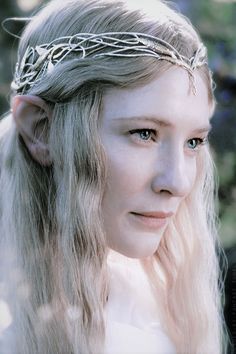 a woman with long blonde hair wearing a crown of silver metal chains on her head