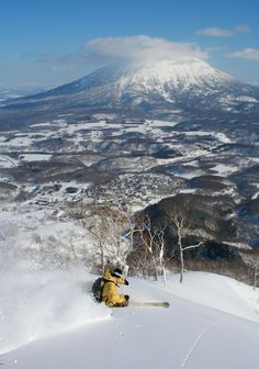 a man riding skis down the side of a snow covered slope next to a mountain