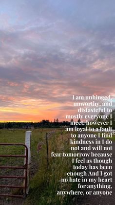 a poem written on the side of a fence in front of a field with a sunset behind it