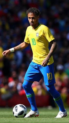 a soccer player in yellow and blue is on the field with a ball near his feet