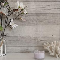 a vase filled with white flowers sitting on top of a table next to a candle