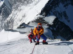 two people climbing up the side of a snow covered mountain