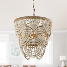 a chandelier hanging from the ceiling in a living room with white walls and furniture