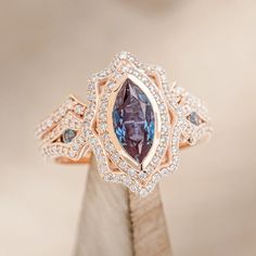 a diamond and blue topaz ring sitting on a piece of wood with diamonds surrounding it