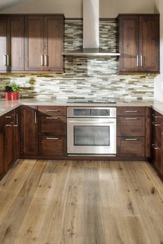 a kitchen with wooden cabinets and stainless steel oven in the center, along with wood flooring