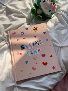 Light pink scrapbook with newspaper lettering spelling senior year. Decorated with puffy heart stickers and multi-colored jewels. Senior Year Scrapbook, Anniversary Scrapbook, Scrapbook Cover, Love Scrapbook, Memory Journal, School Scrapbook, Scrapbook Gift, School Memories