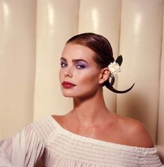 a woman wearing a white dress with a flower in her hair